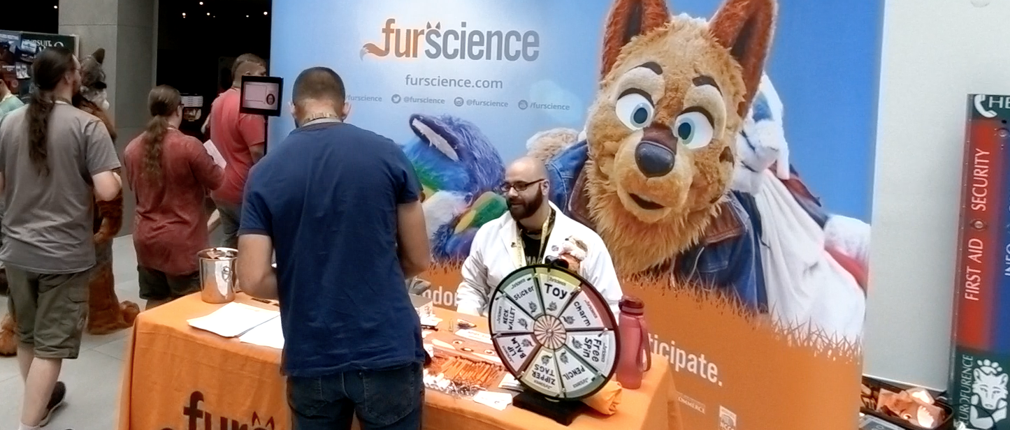 Dr Courtney "Nuka" Plante discussing Furscience's latest research at the Furscience booth with a Eurofurence attendee in Berlin, Germany in 2019
